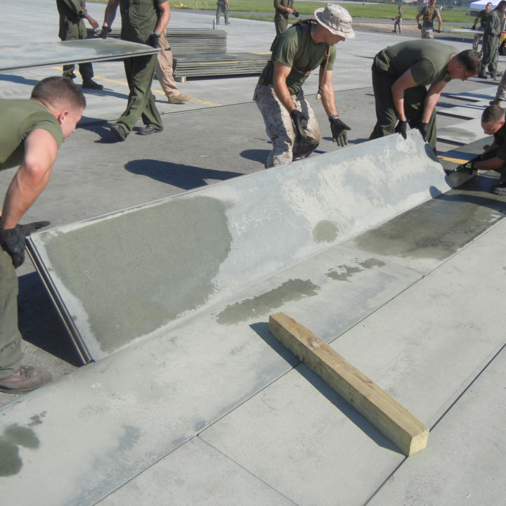 Marines from Marine Corps Air Station, Expeditionary Airfields, Marine Wing Support Squadron 274 put down AM-2 matting on the Delta taxiway at Quantico’s Marine Corps Air Facility. ITAMCO will be replacing the labor-intensive AM-2 matting with a revolutionary product. (Photo by John Holli)