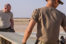 Tech. Sgt. Dan Zimmerman (back) and Senior Airman Thet Tun (front) carry a piece of AM2 matting material, Camp Dwyer, Afghanistan, July, 12, 2016. Zimmerman and Tun constructed a 100’ x 100’ helicopter landing zone out of AM2 matting to support the medical facility at Camp Dwyer. (Courtesy photo by 451 Air Expeditionary Support Squadron)