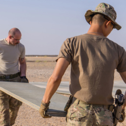 Tech. Sgt. Dan Zimmerman (back) and Senior Airman Thet Tun (front) carry a piece of AM2 matting material, Camp Dwyer, Afghanistan, July, 12, 2016. Zimmerman and Tun constructed a 100’ x 100’ helicopter landing zone out of AM2 matting to support the medical facility at Camp Dwyer. (Courtesy photo by 451 Air Expeditionary Support Squadron)