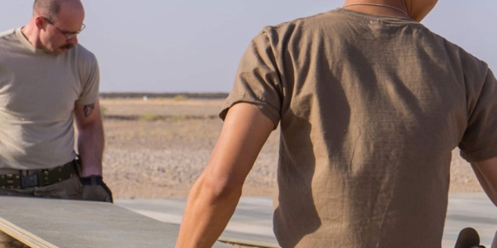 Tech. Sgt. Dan Zimmerman (back) and Senior Airman Thet Tun (front) carry a piece of AM2 matting material, Camp Dwyer, Afghanistan, July, 12, 2016. Zimmerman and Tun constructed a 100’ x 100’ helicopter landing zone out of AM2 matting to support the medical facility at Camp Dwyer. (Courtesy photo by 451 Air Expeditionary Support Squadron)