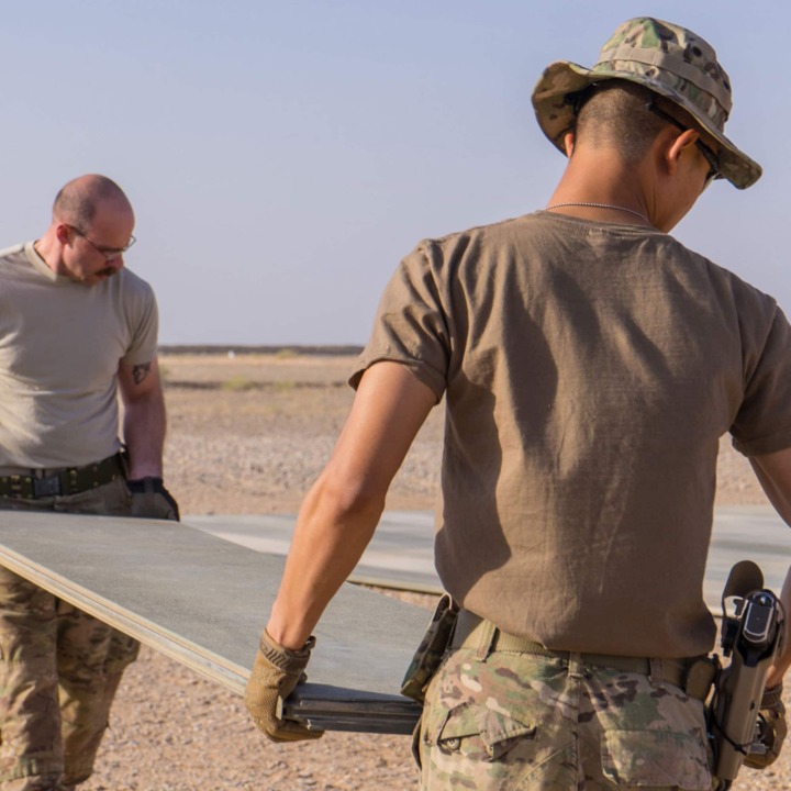 Tech. Sgt. Dan Zimmerman (back) and Senior Airman Thet Tun (front) carry a piece of AM2 matting material, Camp Dwyer, Afghanistan, July, 12, 2016. Zimmerman and Tun constructed a 100’ x 100’ helicopter landing zone out of AM2 matting to support the medical facility at Camp Dwyer. (Courtesy photo by 451 Air Expeditionary Support Squadron)